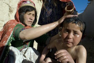 Matka myje dítě na dvorku